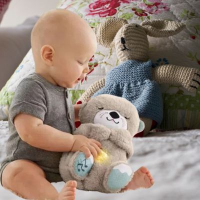 Doudou loutre beige avec enfant souriant peluche loutre sur le lit qui joue tranquillement