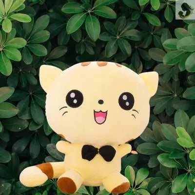 Peluche kawaii-peluche chat jaune souriant et heureux assis parmi des feuillages verts