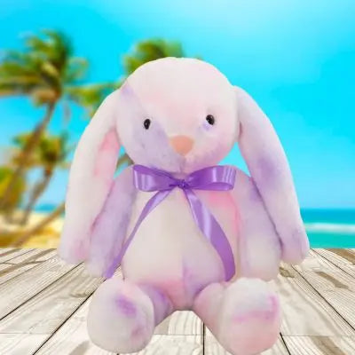 Peluche lapin-doudou soyeux à la couleur pastel assis à la fenêtre donnant sur la plage