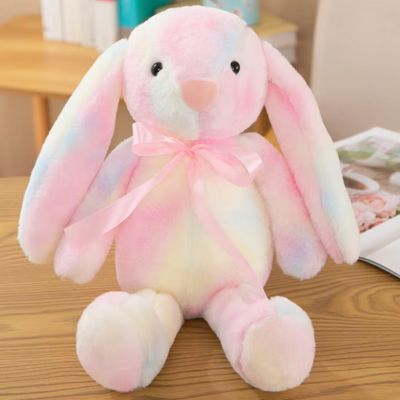 Peluche lapin rose-doudou au ruban satiné rose assis sur une table trop doux