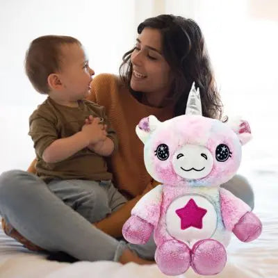 peluche licorne rose entre l'heureuse maman et son bébé dans la maison