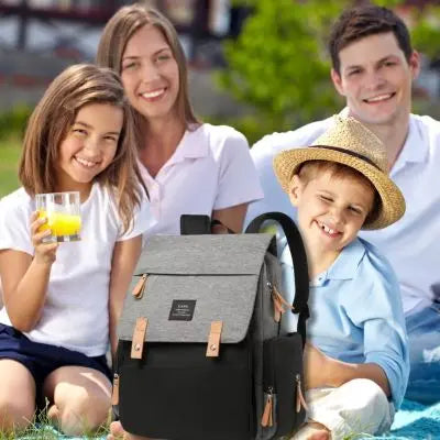 sac a langer de couleur noire et grise avec famille heureuse assise au camping