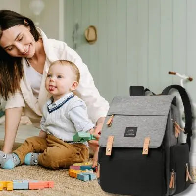sac a langer-noir-et-gris-avec-maman-qui-joue-avec-bébé